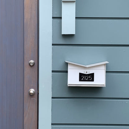 Wall Mount Mailbox mounted to outdoor wall panels. ButterFly Box in arctic white and jet black